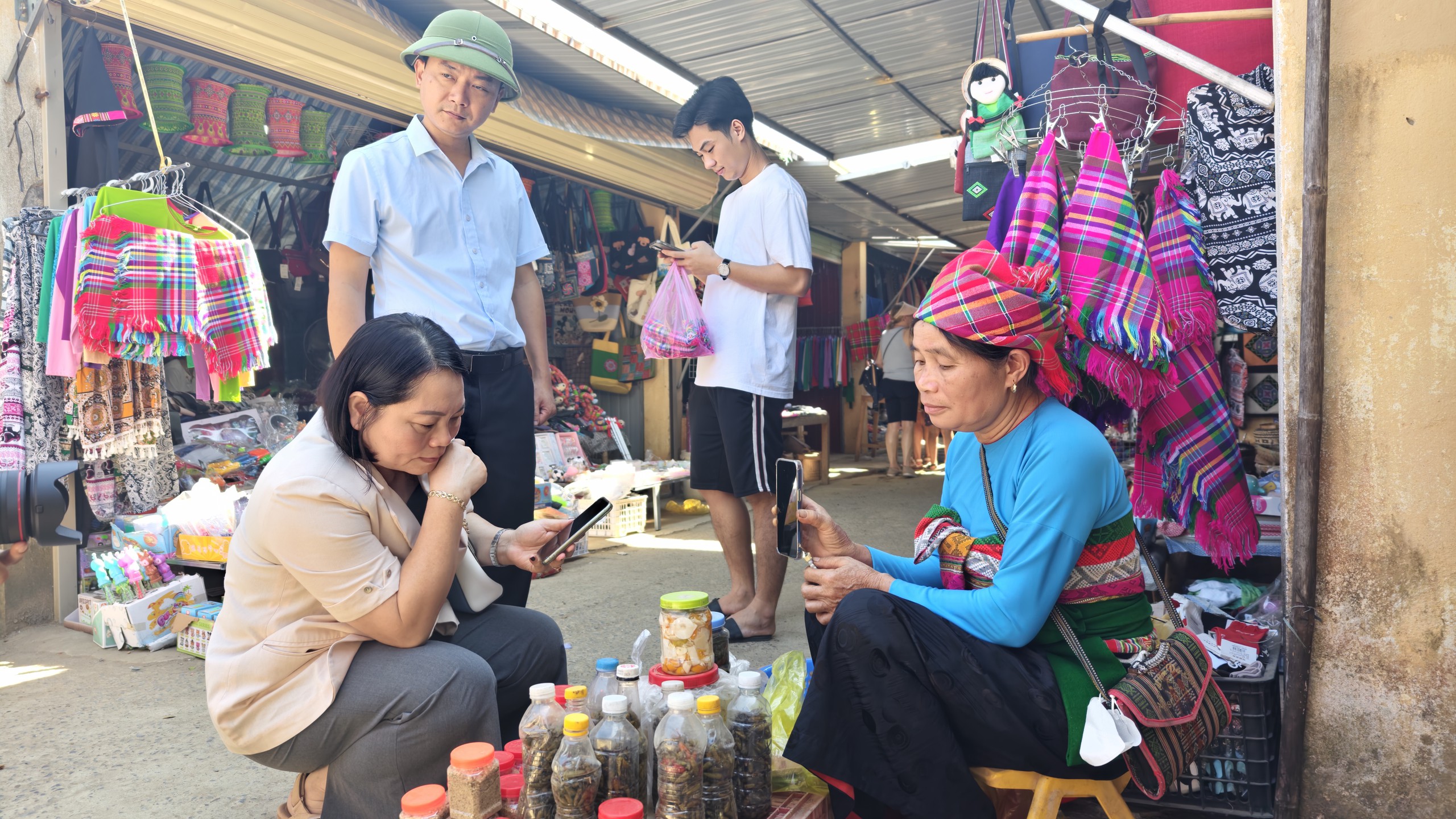 Bà Bùi Thị Hoa - Bí thư Đảng ủy, Chủ tịch HĐND xã Pù Luông (ngồi bên trái) trước sạp hàng nhỏ ở chợ Phố Đoàn. Ảnh: Huy Thông