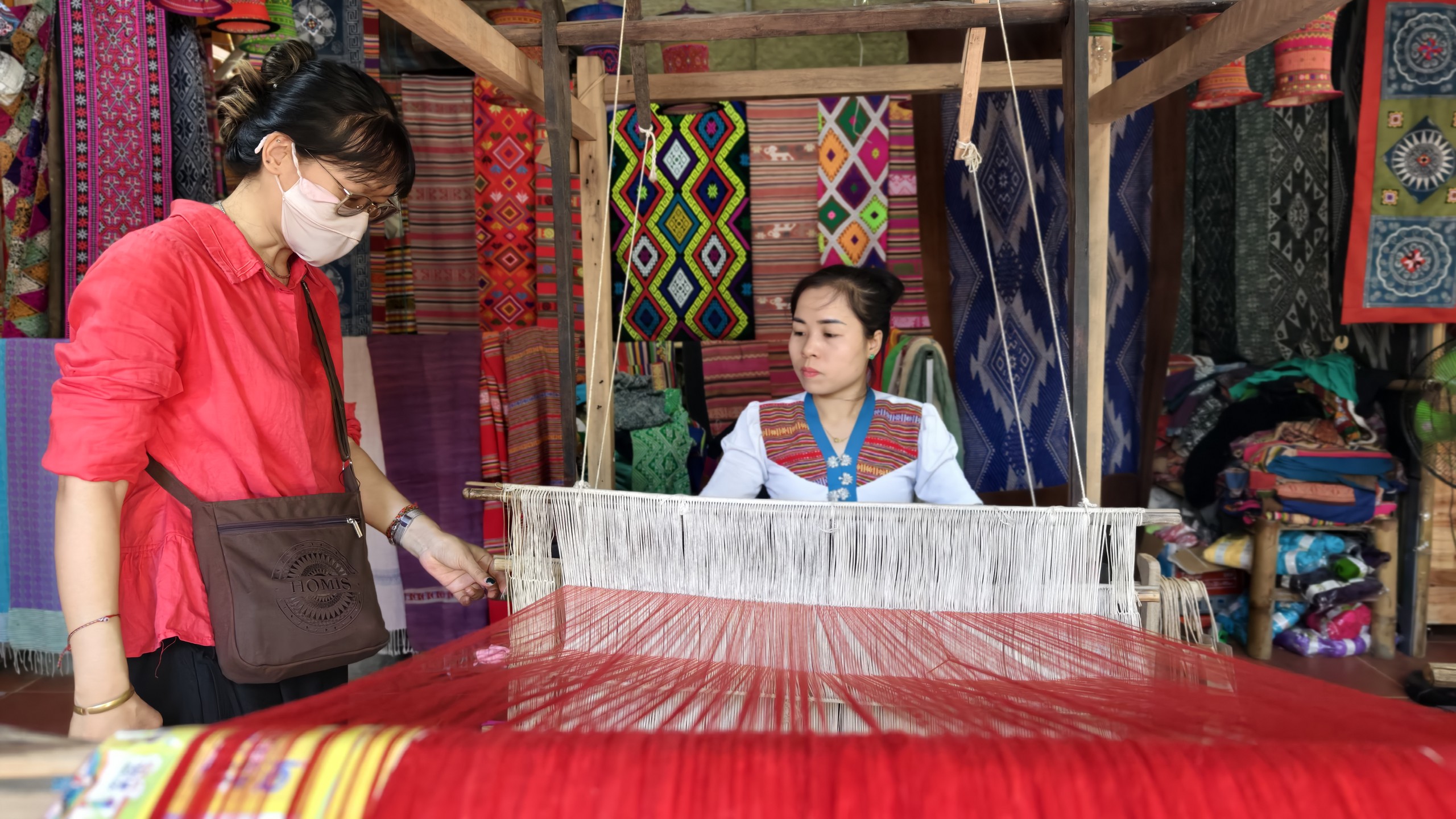Cụ Hà Thị Nhân hướng dẫn chị Nhân Ái - du khách đến từ TP.HCM dệt vải. Ảnh: Huy Thông - ảnh 4