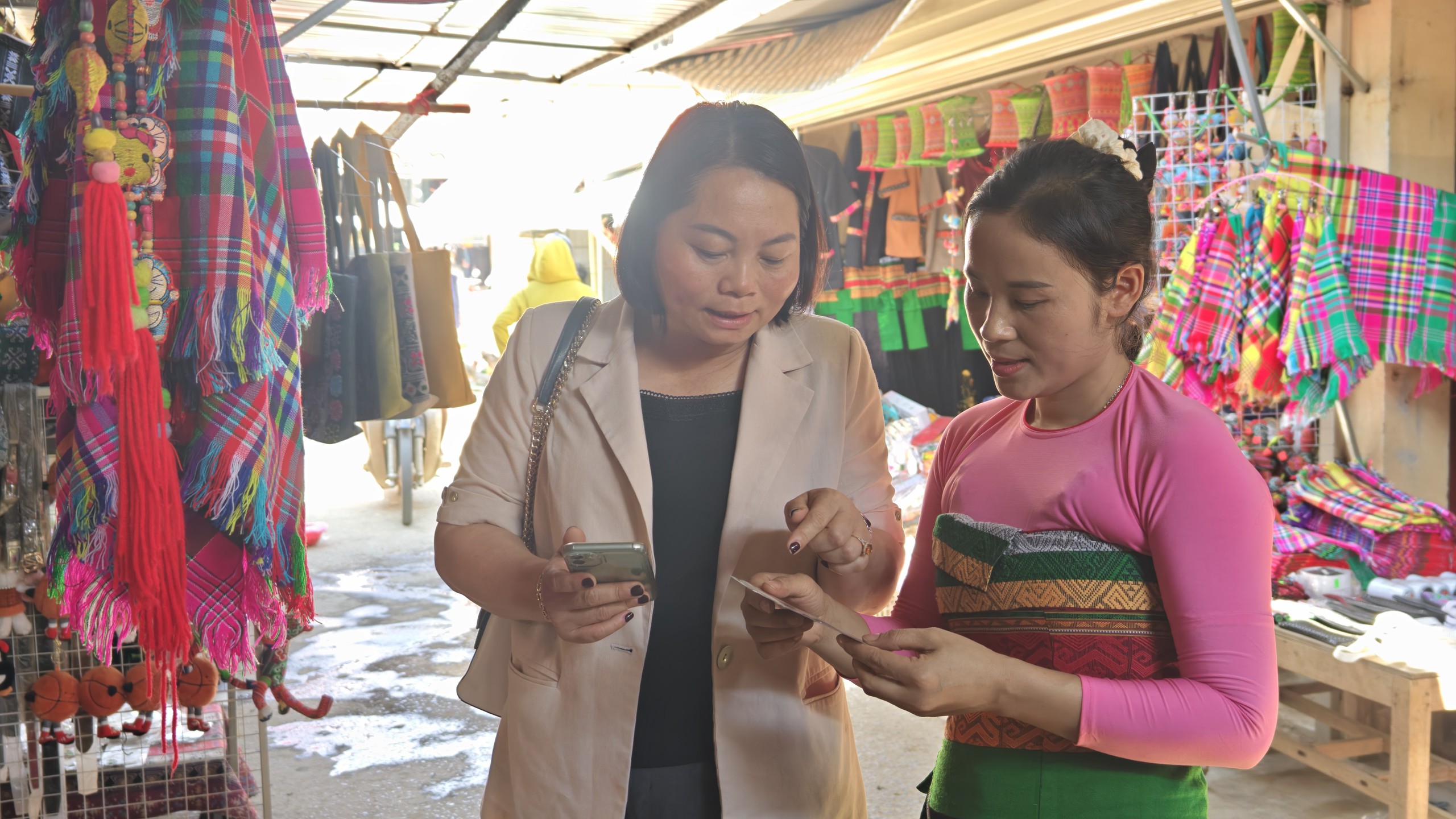 Bà Bùi Thị Hoa hỏi thăm chị Hà Thị Giáo về mã QR. Ảnh: Huy Thông