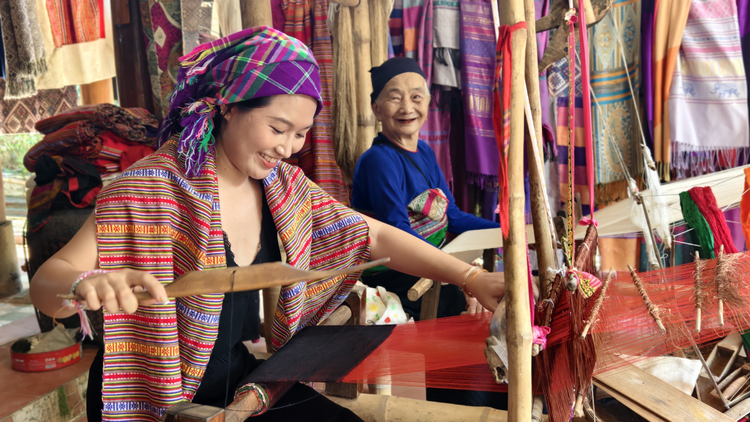 Cụ Hà Thị Nhân hướng dẫn chị Nhân Ái - du khách đến từ TP.HCM dệt vải. Ảnh: Huy Thông - ảnh 2