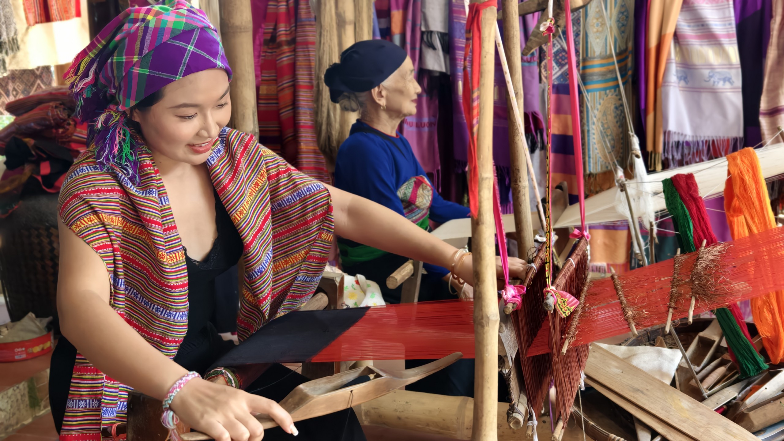 Cụ Hà Thị Nhân hướng dẫn chị Nhân Ái - du khách đến từ TP.HCM dệt vải. Ảnh: Huy Thông - ảnh 3