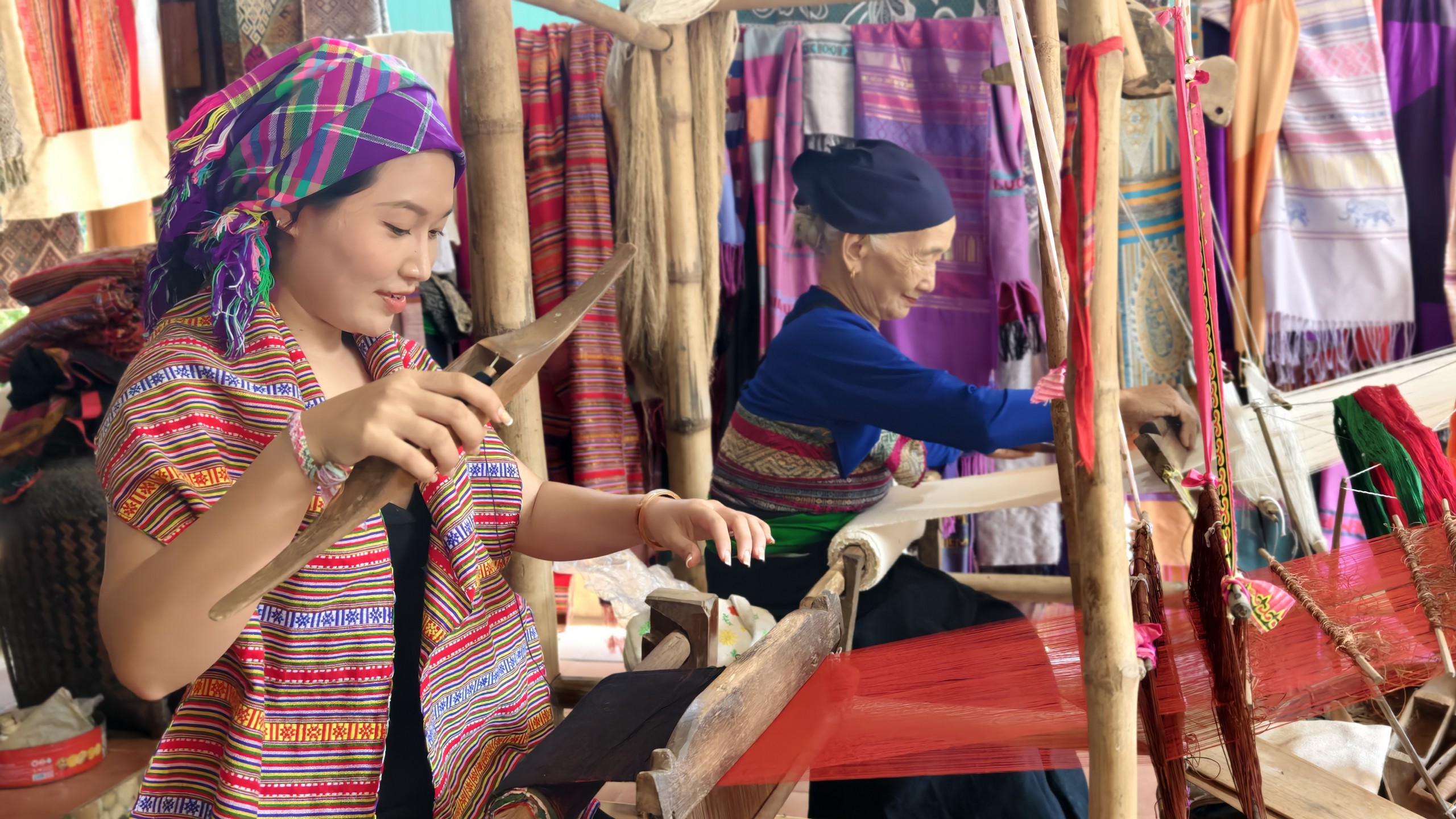 Cụ Hà Thị Nhân hướng dẫn chị Nhân Ái - du khách đến từ TP.HCM dệt vải. Ảnh: Huy Thông - ảnh 5