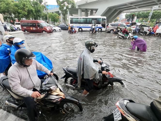 Trong ảnh: Người dân vất vả lưu thông trên tuyến đường bị ngập. Ảnh: Hồng Giang - TTXVN.