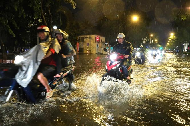 Trong ảnh: Mưa lớn khiến một số tuyến đường ngập úng, gây khó khăn cho người tham gia giao thông. Ảnh: Thành Đạt - TTXVN