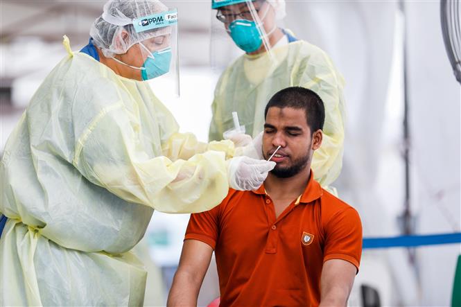 Trong ảnh: Nhân viên y tế lấy mẫu dịch xét nghiệm COVID-19 cho người dân tại Singapore ngày 15/5/2020. Ảnh: AFP/ TTXVN