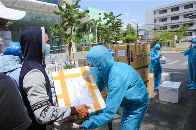 Trong ảnh: Người dân gửi các nhu yếu phẩm thiết yếu cho đội ngũ y tế tại khu vực bị cách ly, phong tỏa. Ảnh: Trần Lê Lâm - TTXVN