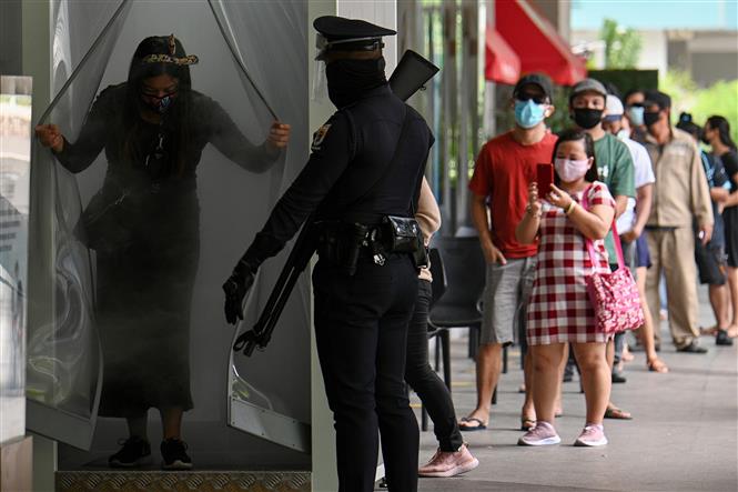 Trong ảnh: Cảnh sát gác bên ngoài một trung tâm mua sắm để nhắc nhở người dân thực hiện tốt các biện pháp phòng dịch COVID-19 tại Manila, Philippines. Ảnh: AFP/TTXVN