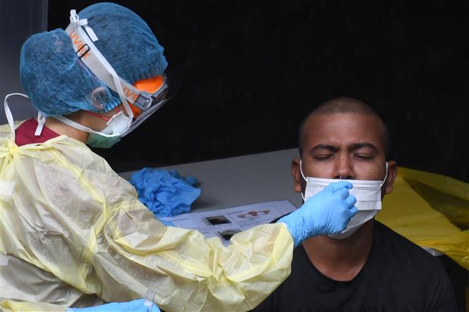  Nhân viên y tế lấy mẫu dịch xét nghiệm COVID-19 cho người dân tại Singapore ngày 27/4/2020. Ảnh: AFP/TTXVN