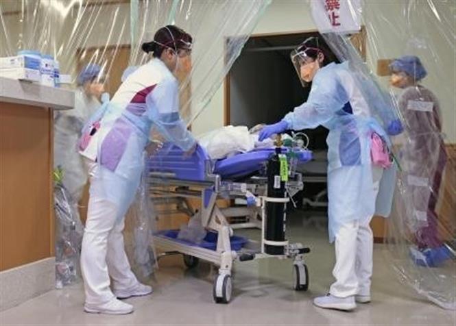 Trong ảnh: Nhân viên y tế chuyển bệnh nhân nhiễm COVID-19 tới bệnh viện ở tỉnh Aichi, Nhật Bản. Ảnh: Kyodo/TTXVN