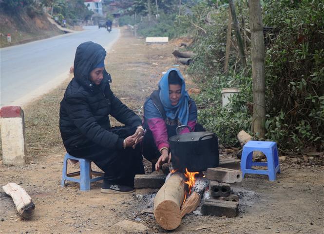 Người dân sinh sống dưới chân đèo Pha Đin, cạnh QL6 đốt lửa sưởi ấm, chống chọi với giá lạnh. Ảnh: TTXVN