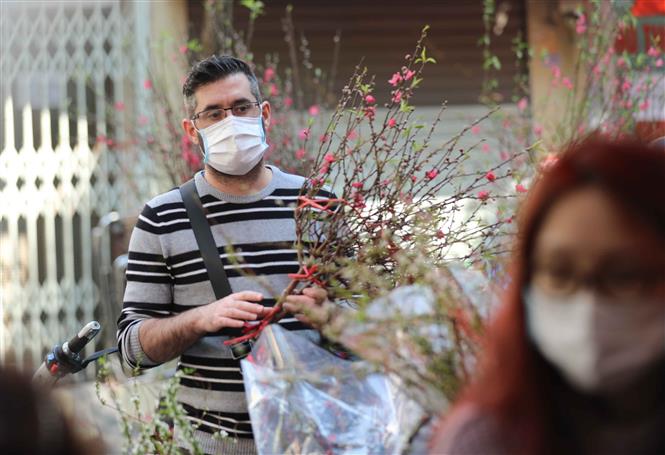 Trong ảnh: Một người nước ngoài đi chợ hoa Tết truyền thống thực hiện nghiêm túc việc đeo khẩu trang để phòng chống dịch. Ảnh: Thanh Tùng - TTXVN