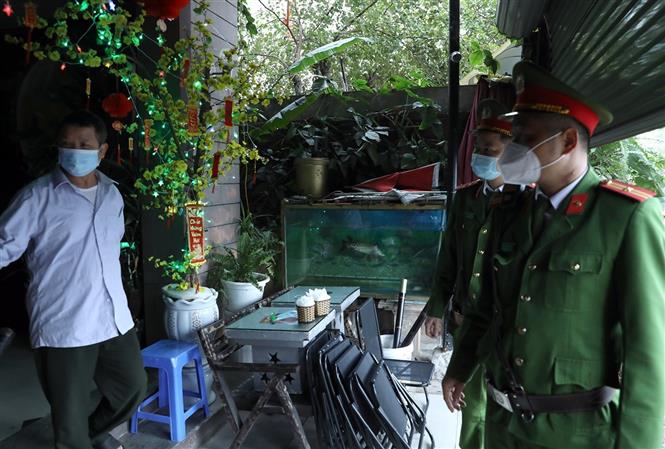 Lực lượng Công an nhắc nhở người dân việc thực hiện đóng cửa quán cà phê tại khu đô thị Văn Quán, quận Hà Đông. Ảnh: Phan Tuấn Anh - TTXVN