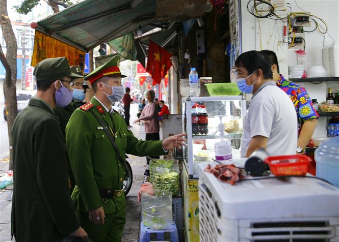  Lực lượng chức năng phường Hàng Mã, quận Hoàn Kiếm đề nghị các hộ kinh doanh thực hiện nghiêm quyết định của Ban chỉ đạo phòng, chống dịch COVID-19 TP Hà Nội. Ảnh: Doãn Tấn - TTXVN