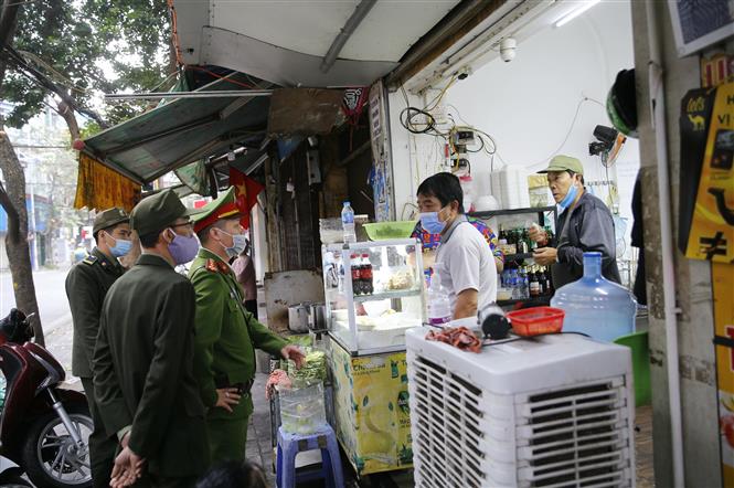 Lực lượng chức năng phường Hàng Mã, quận Hoàn Kiếm đề nghị các hộ kinh doanh thực hiện nghiêm quyết định của Ban chỉ đạo phòng, chống dịch COVID-19 TP Hà Nội. Ảnh: Doãn Tấn - TTXVN