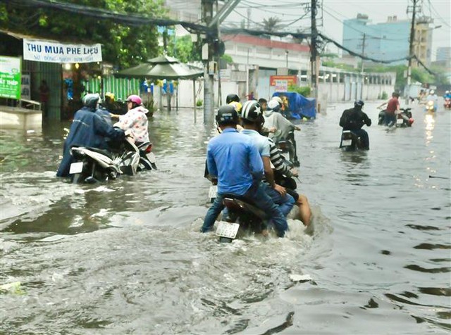 Trong ảnh: Các phương tiện gặp khó khăn trong dòng nước ngập lút bánh xe trên đường Tô Ngọc Vân (quận Thủ Đức). Ảnh: Hồng Giang - TTXVN