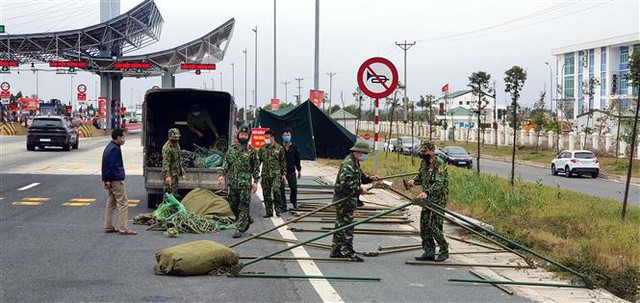 Trong ảnh: Lực lượng chức năng dựng lán chuẩn bị cho công tác phòng chống COVID-19 tại chốt trạm cầu Bạch Đằng, thị xã Quảng Yên. Ảnh: TTXVN