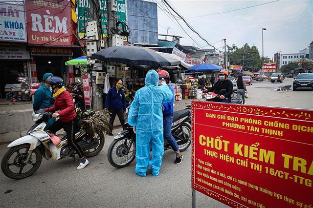 Trong ảnh: Lực lượng chức năng lập chốt thực hiện nghiêm việc đo thân nhiệt, nhắc nhở người dân tuân thủ đeo khẩu trang tại các điểm chợ. Ảnh: Trọng Đạt-TTXVN