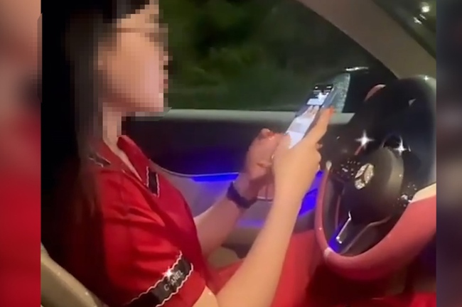 Nữ tài xế ô tô buông hai tay, 'dán mắt' vào điện thoại để quay TikTok bị tước bằng 2 tháng - Ảnh 1.